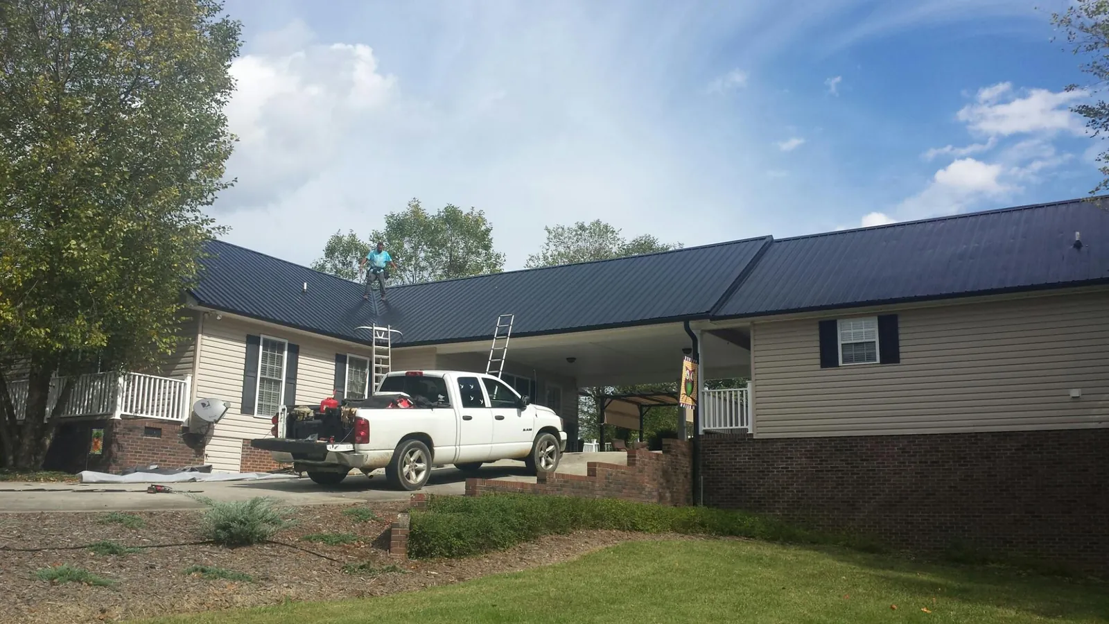 Black metal roof over a home and attached breezeway with ladders set in Laredo