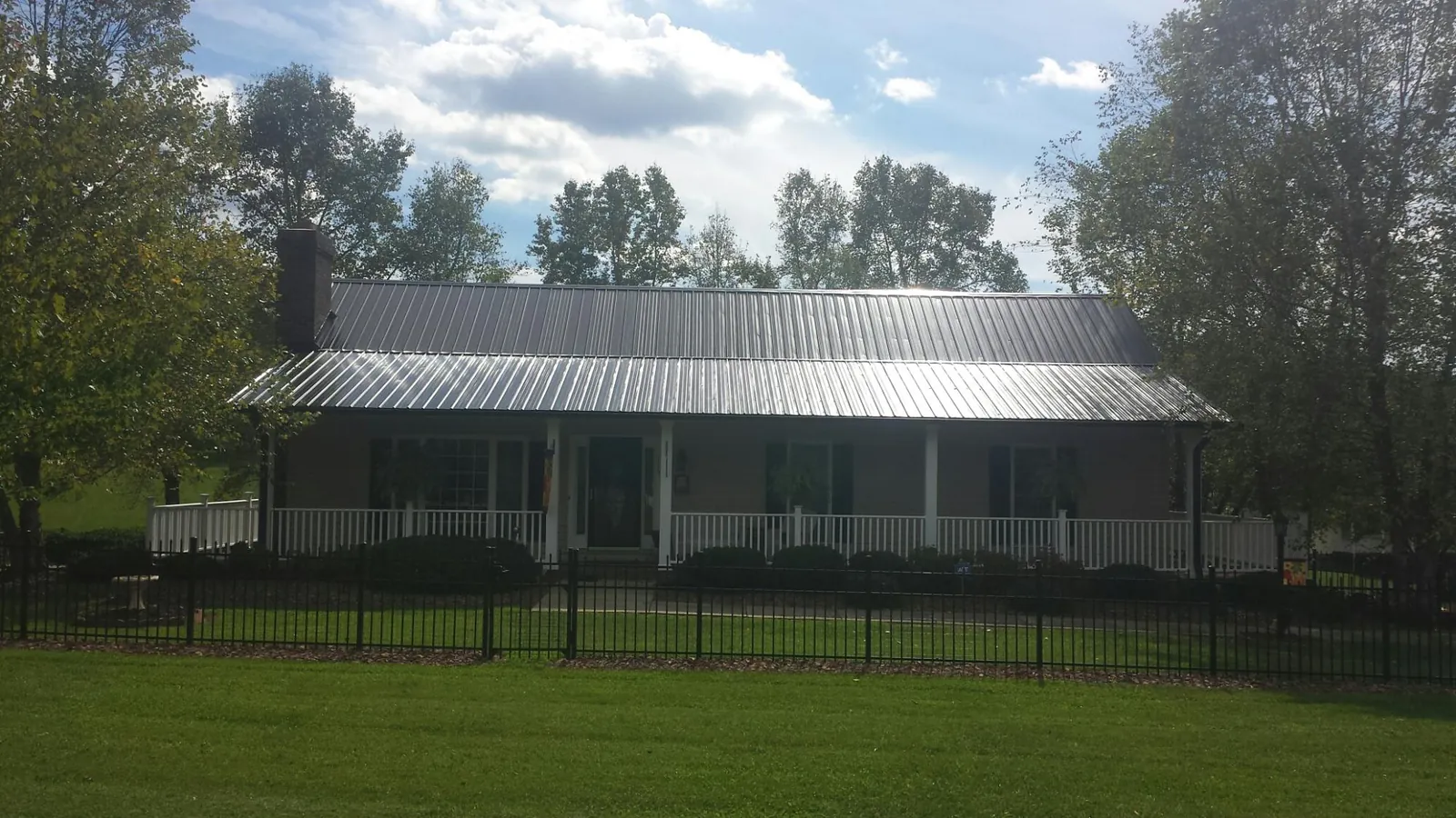 Gray metal roof on a brick ranch with a full width front porch — Gutter Guard Installation work by our crew in Laredo