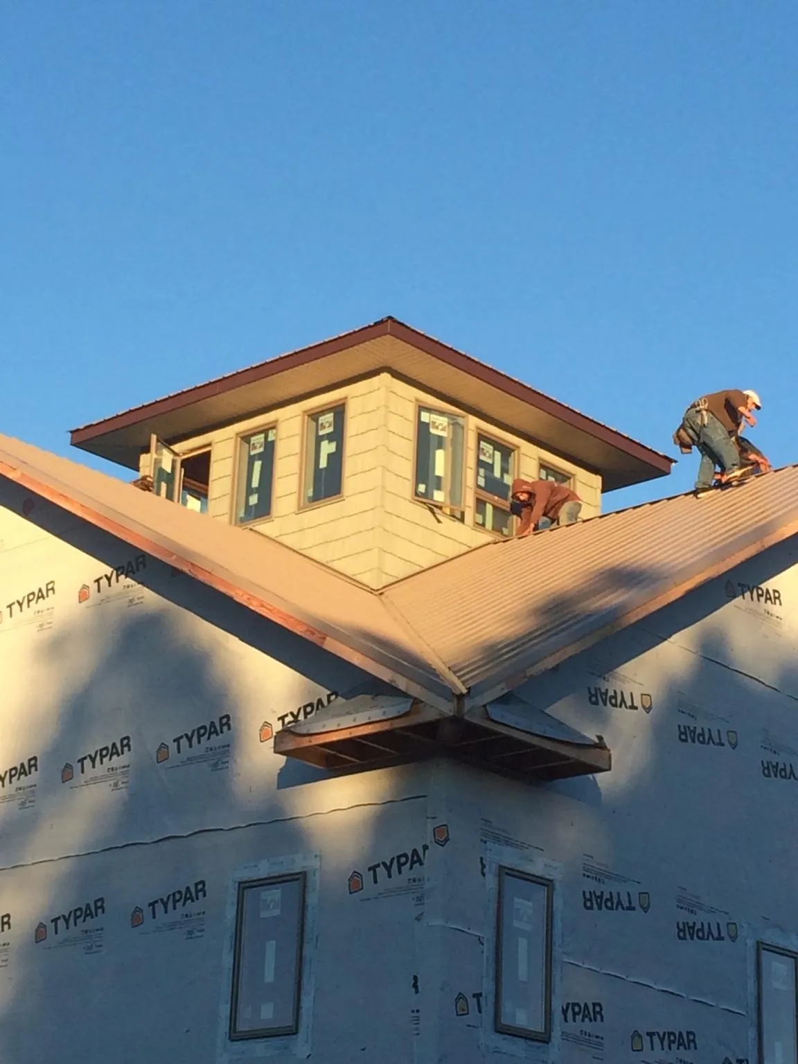 Roofers working around a rooftop cupola on a new metal roof at sunset — Roof Waterproofing in Laredo by Roofing Brothers